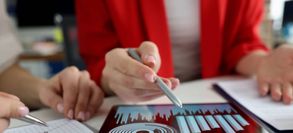 Business women studying charts and diagrams on digital tablet closeup